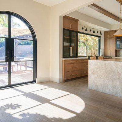 Interior with arched door to patio, wood cabinets, and kitchen island. Sunlight on floor.