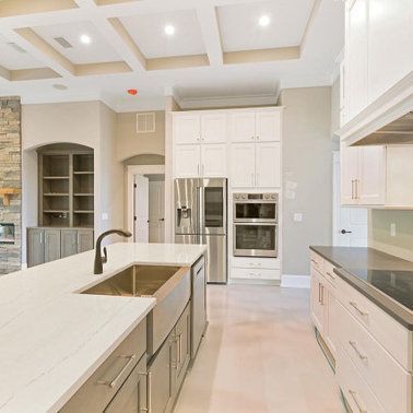 Modern kitchen with white cabinets, stainless steel appliances, and a large island with a sink.