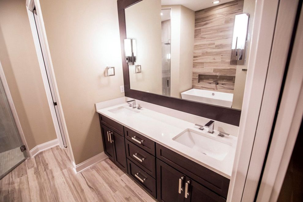Modern bathroom with double sink vanity, large mirror, and wood-look tile.