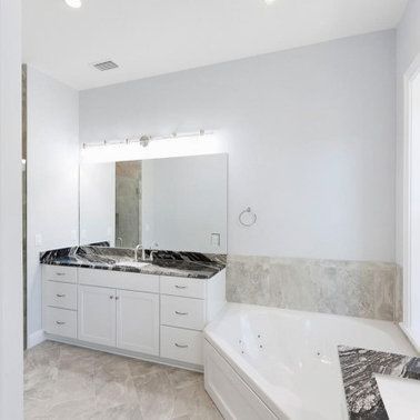 White bathroom with a white vanity, black granite countertop, and a white bathtub.
