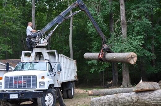 A man is sitting on top of a truck with a crane attached to it.