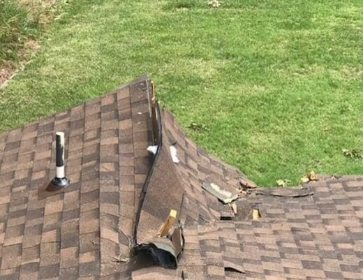 A roof with a hole in it is sitting on top of a lush green field.