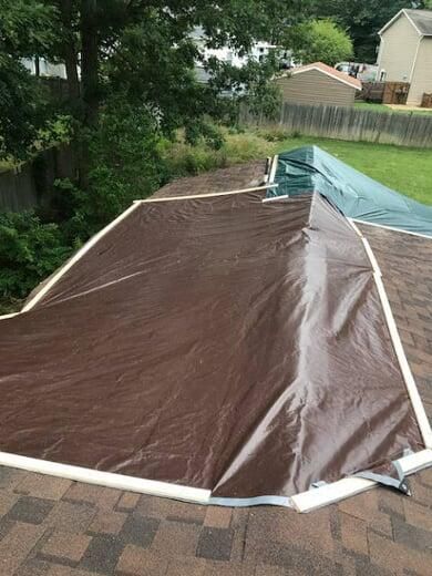 A brown tarp is sitting on top of a brick roof.