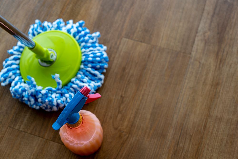 Mop and Spray Bottle on Wooden Floor — Cairns Local Cleaning Services in Redlynch, QLD