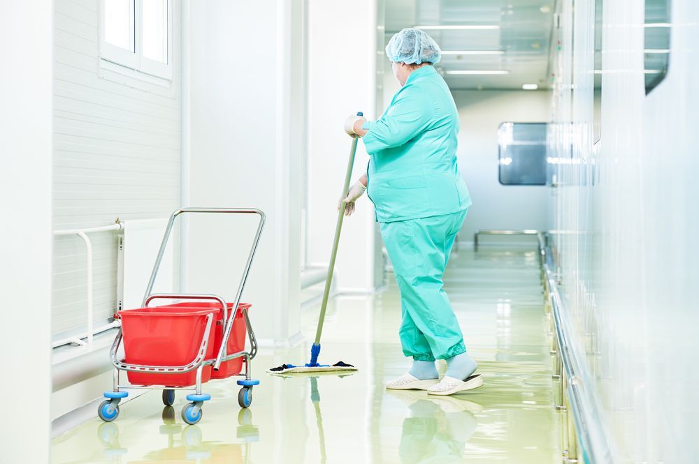 Person in Green Scrubs Mops a Hospital Hallway — Cairns Local Cleaning Services in Woree, QLD