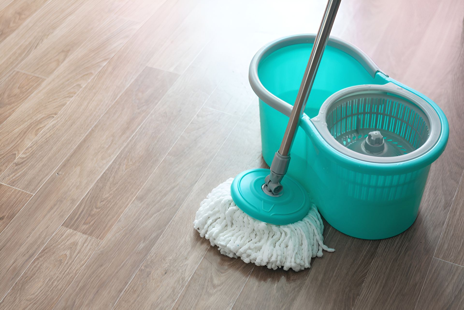 Turquoise Mop and Bucket on a Light Wood-look Floor — Cairns Local Cleaning Services in Smithfield, QLD