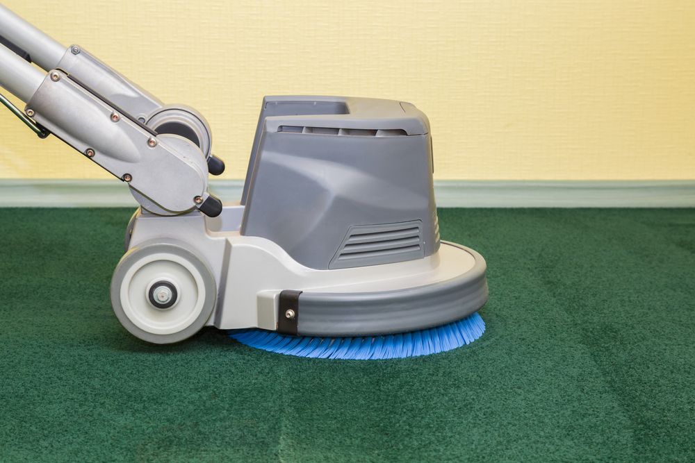 A Floor-cleaning Machine With a Blue Brush Cleans a Green Carpet — Cairns Local Cleaning Services in Woree, QLD