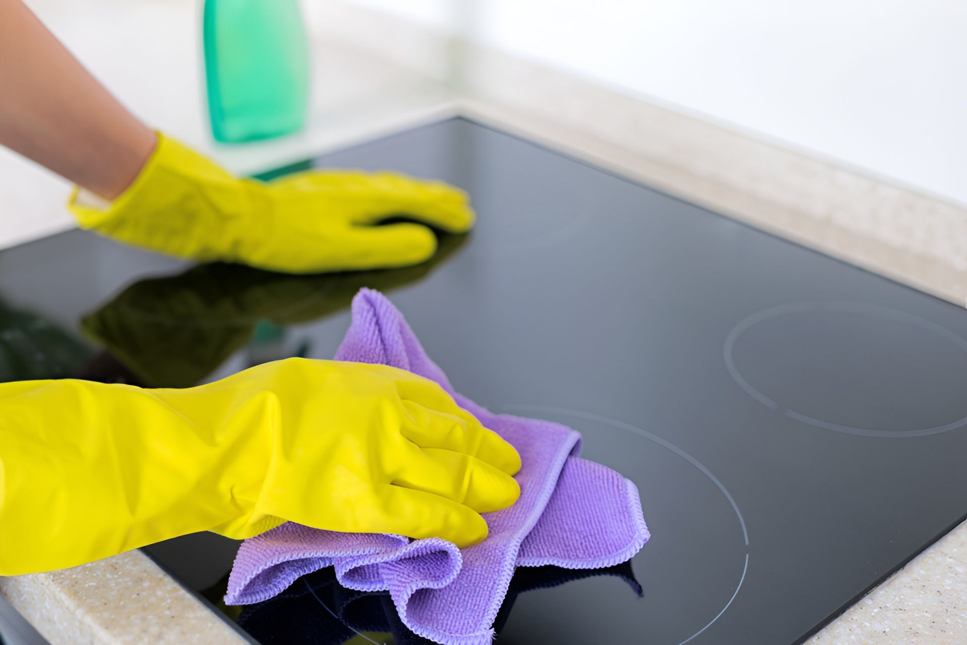 Person Wearing Yellow Gloves Cleaning a Black Stovetop — Cairns Local Cleaning Services in Woree, QLD