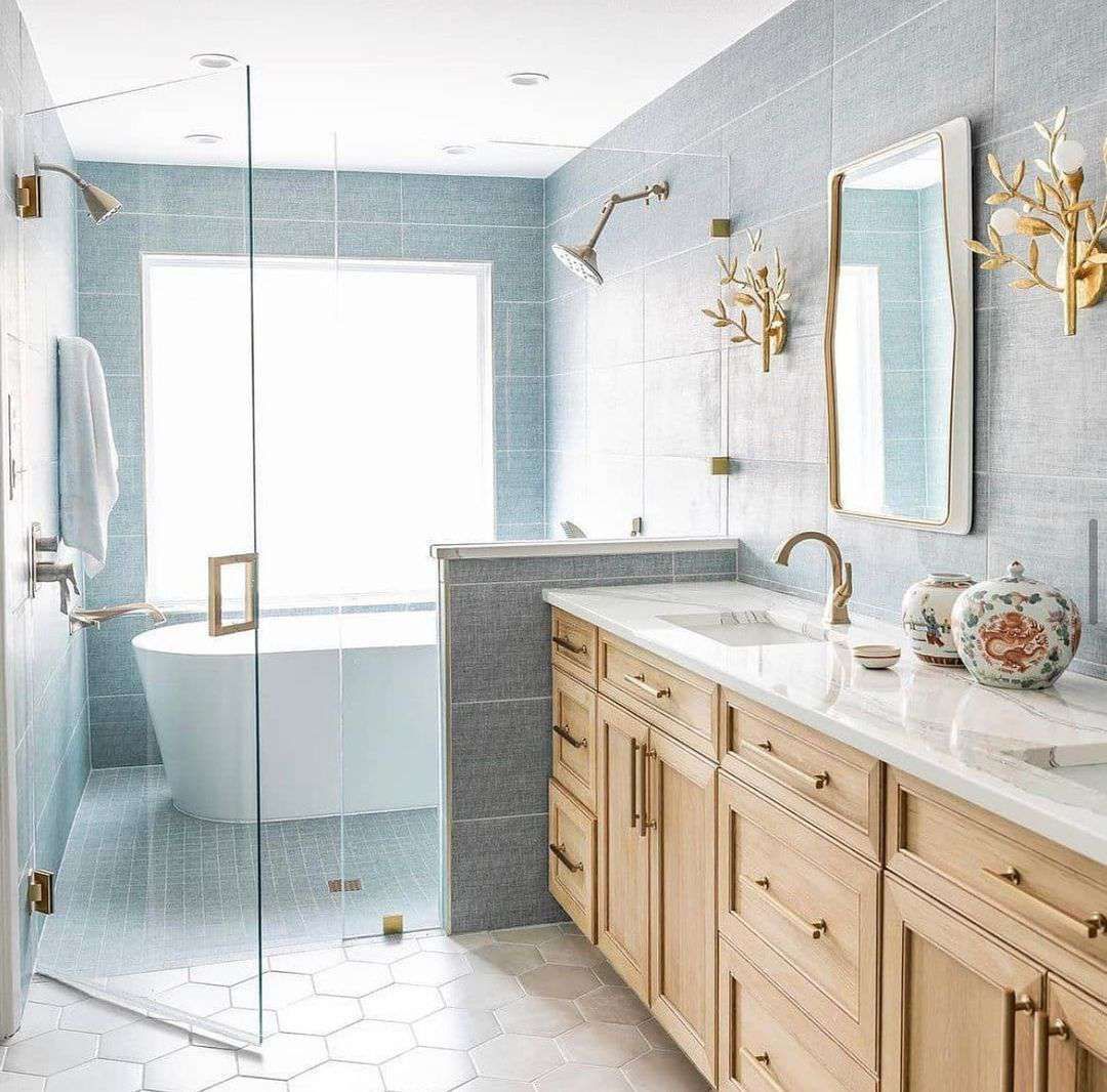 Workers in an orange vest installing large blue pipes in a trench, surrounded by debris.