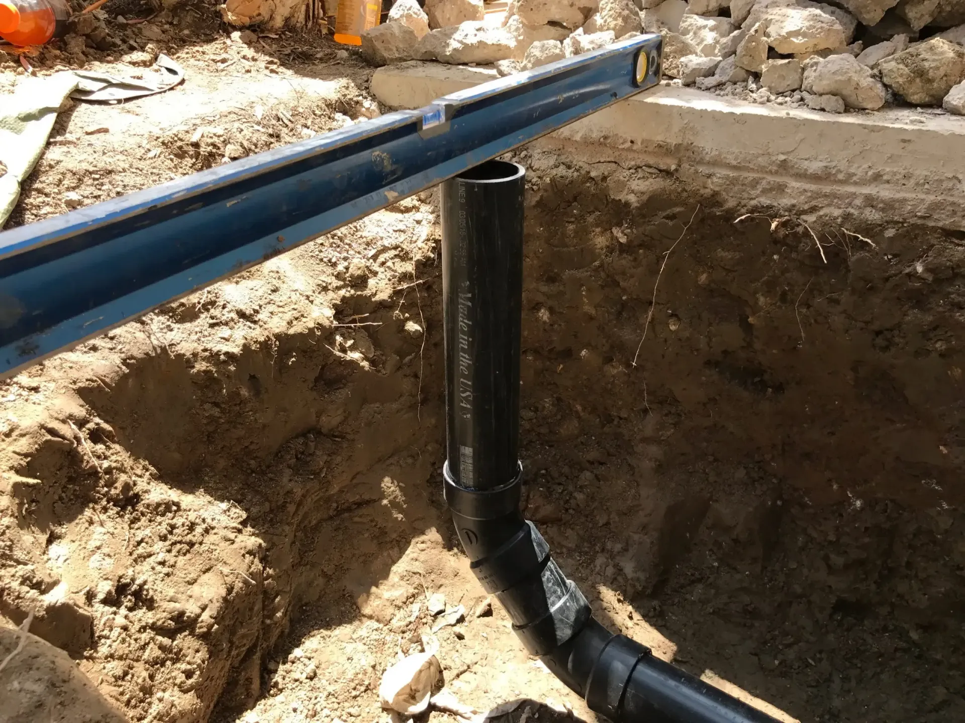 Two beige generators with black panels and cables on a gravel surface near a fence.