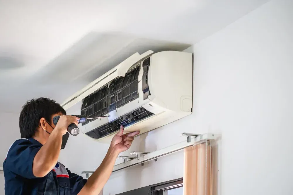 Electrician working on a circuit breaker panel with a screwdriver.