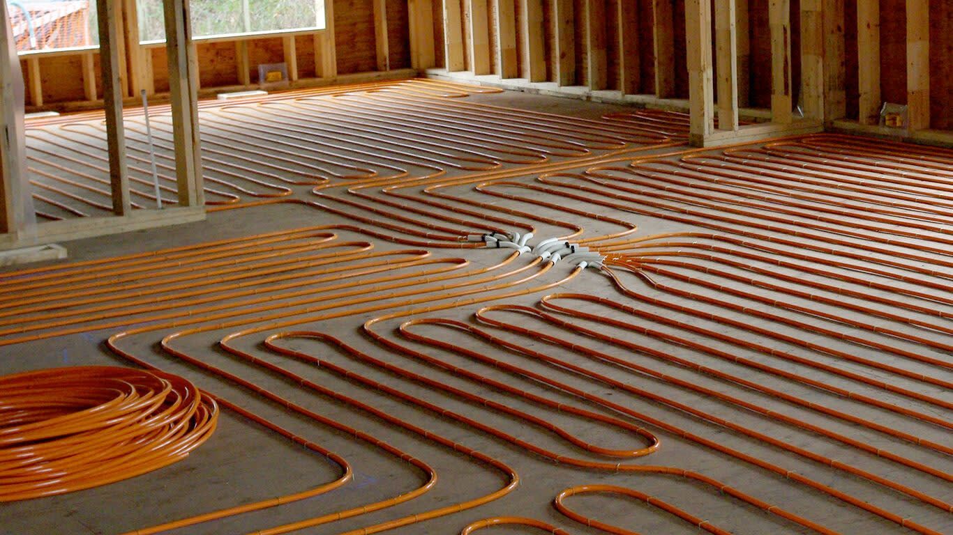 Driveway construction: red radiant heating tubes laid on wire mesh in front of a large house with a gray roof.