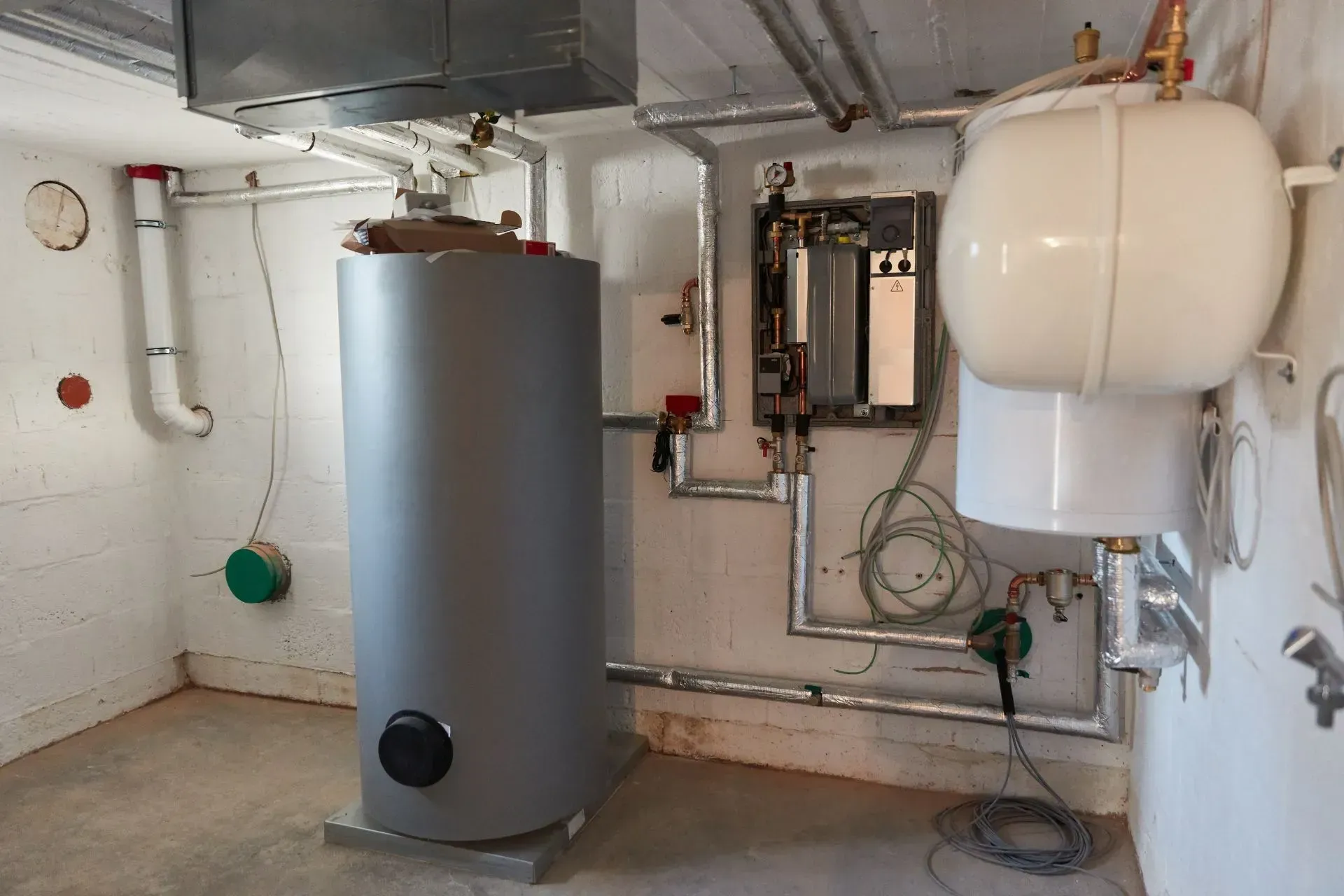 Interior of a basement mechanical room with water heater, expansion tank, and pipes.