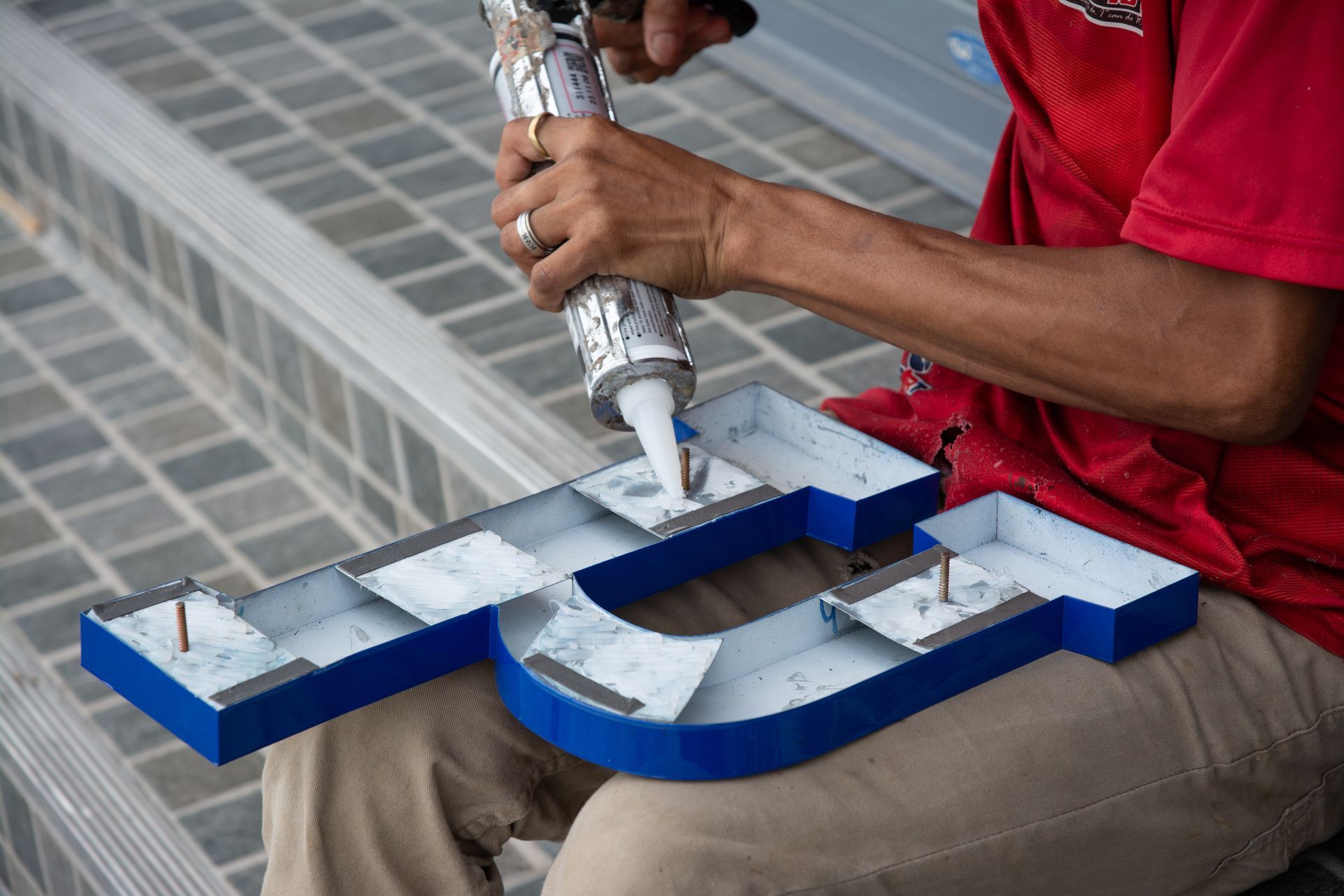 Worker installing lettering on a commercial metal sign. Worker installing lettering on a commercial metal sign.