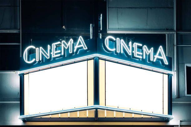 Illuminated commercial sign on a movie theater building.