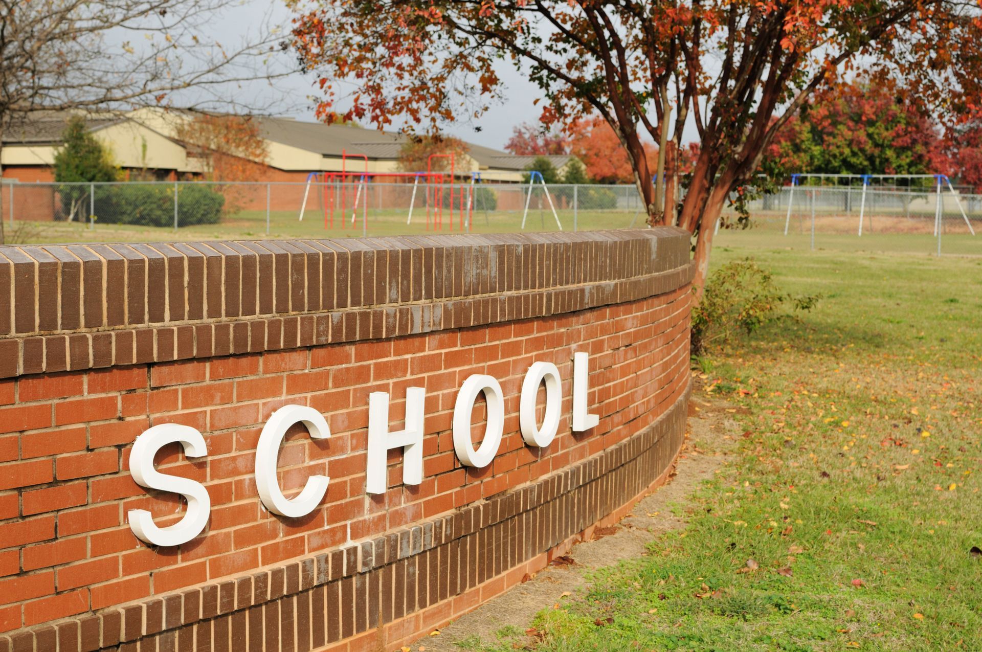 School sign with playground in background. School sign with playground in background.