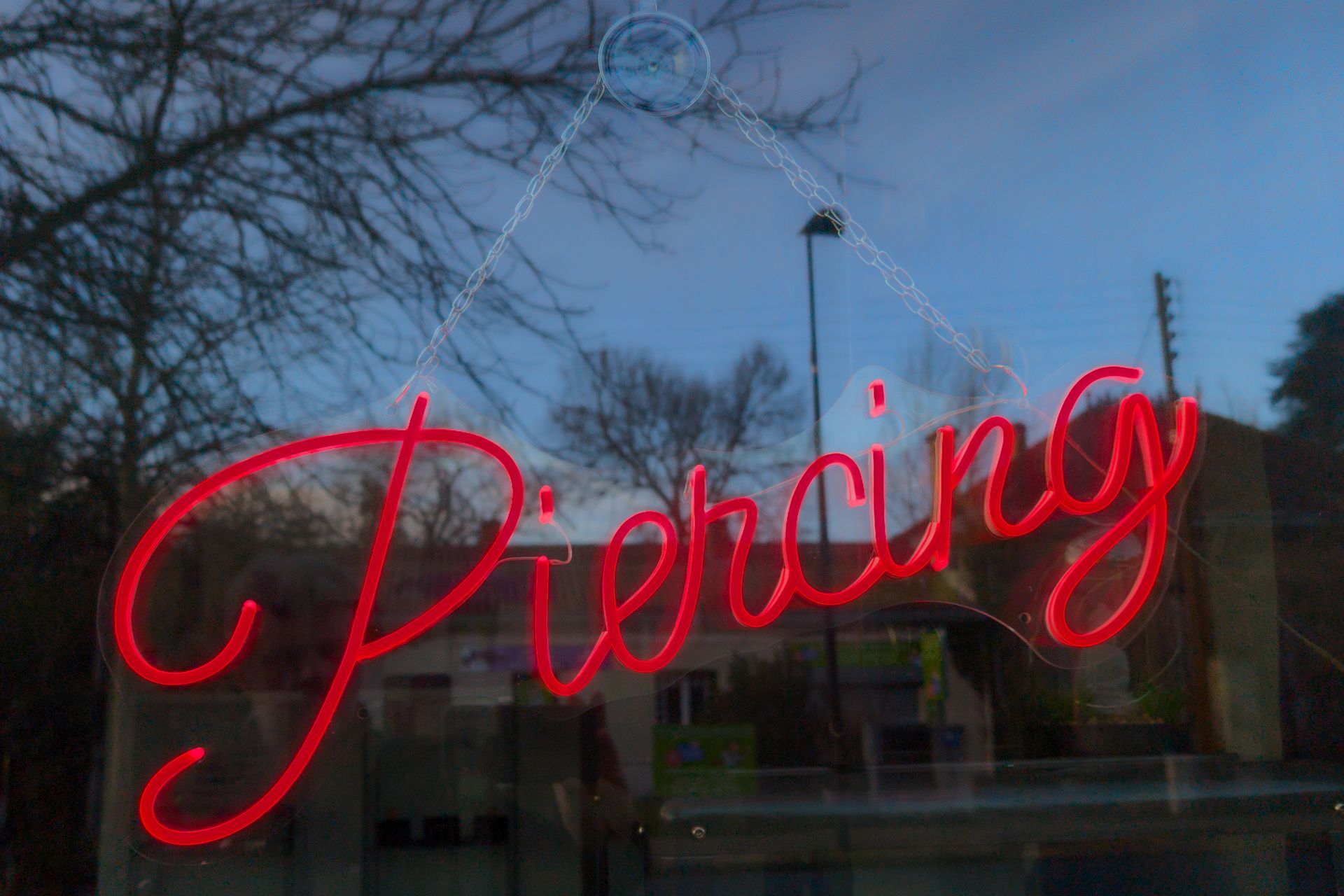 A piercing LED neon sign text on a body pierce shop window facade