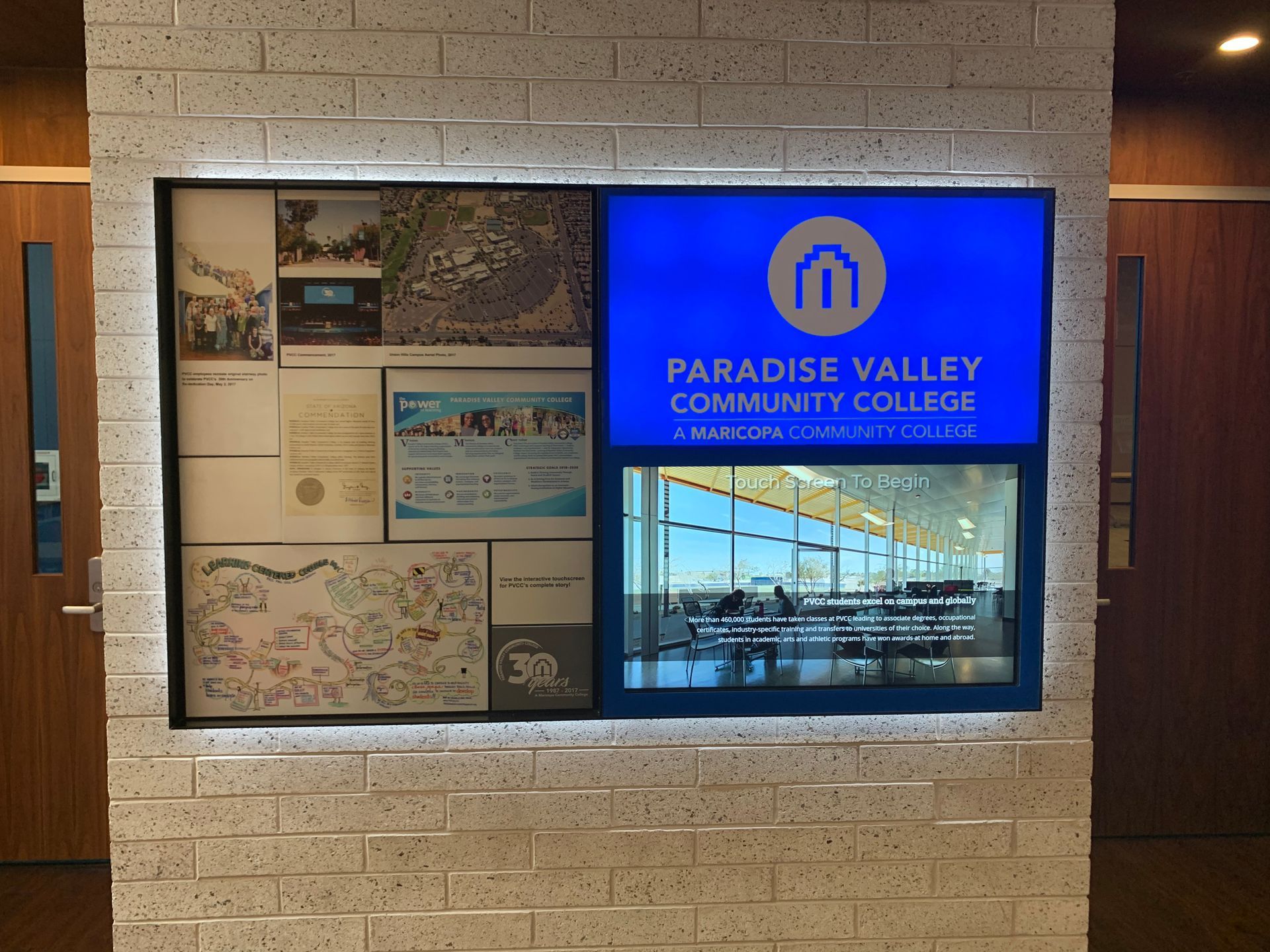 Display at Paradise Valley Community College, with logo and other images, on a brick wall.
