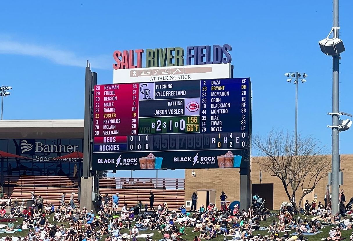 Scoreboard at Salt River Fields displaying a baseball game with fans in the stands on a sunny day.