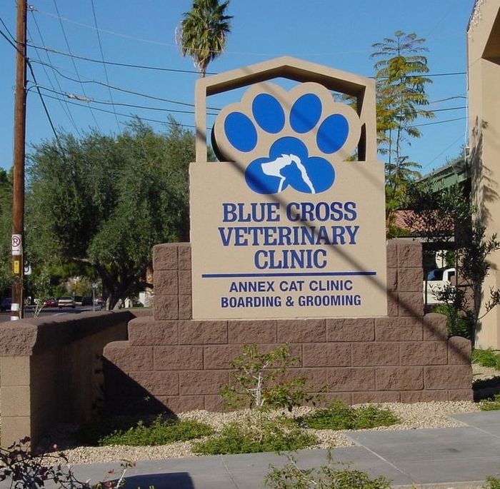 Sign for Blue Cross Veterinary Clinic. Features a blue paw print logo, clinic name, and services.