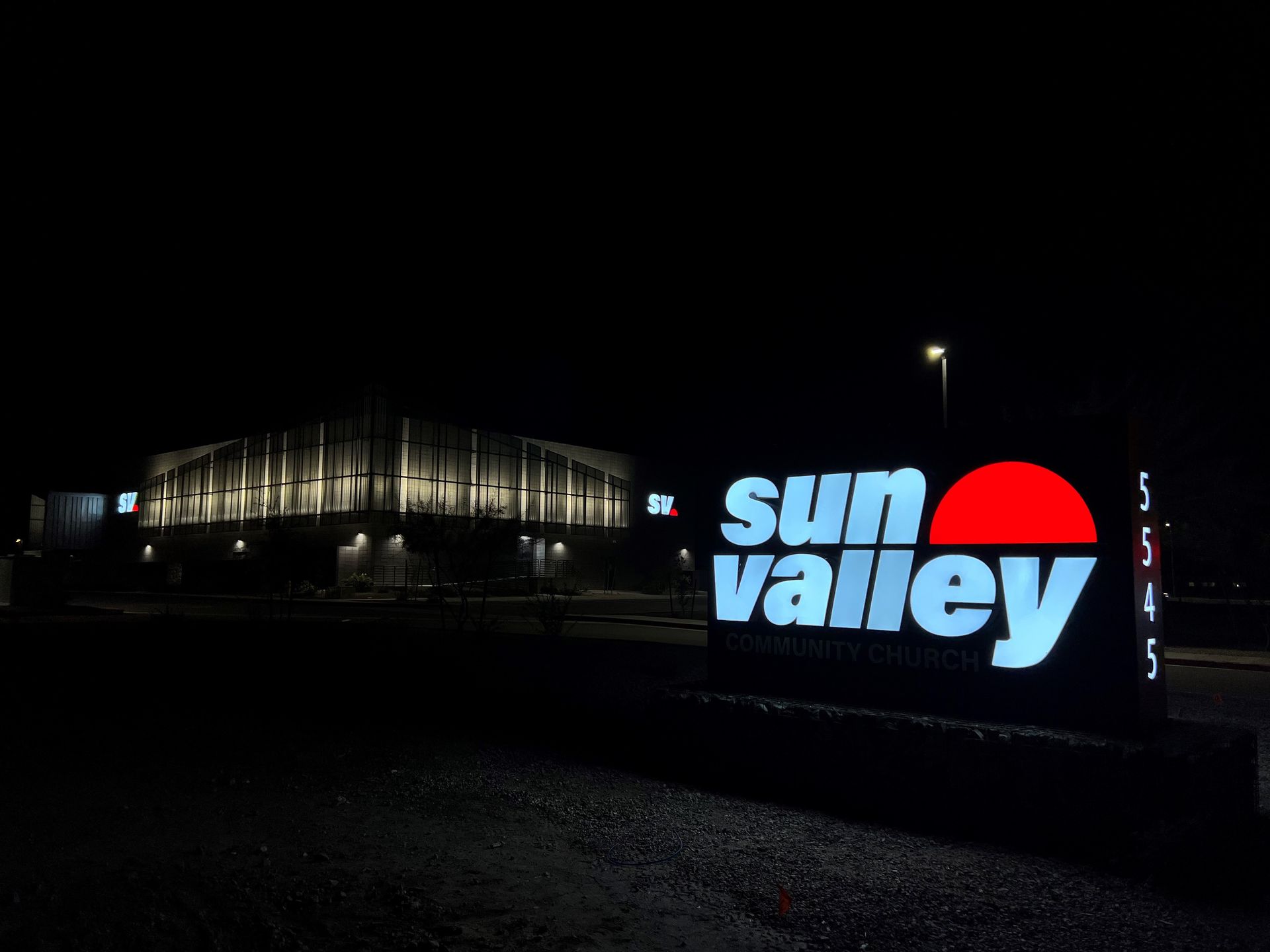 Illuminated Sun Valley sign at night with a building in the background.