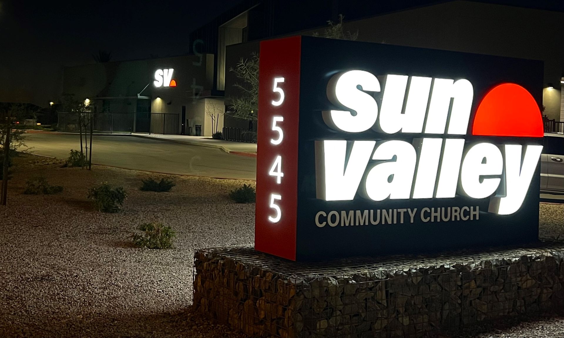 Illuminated sign for Sun Valley Community Church at 5545, with a red sun symbol on a dark night.
