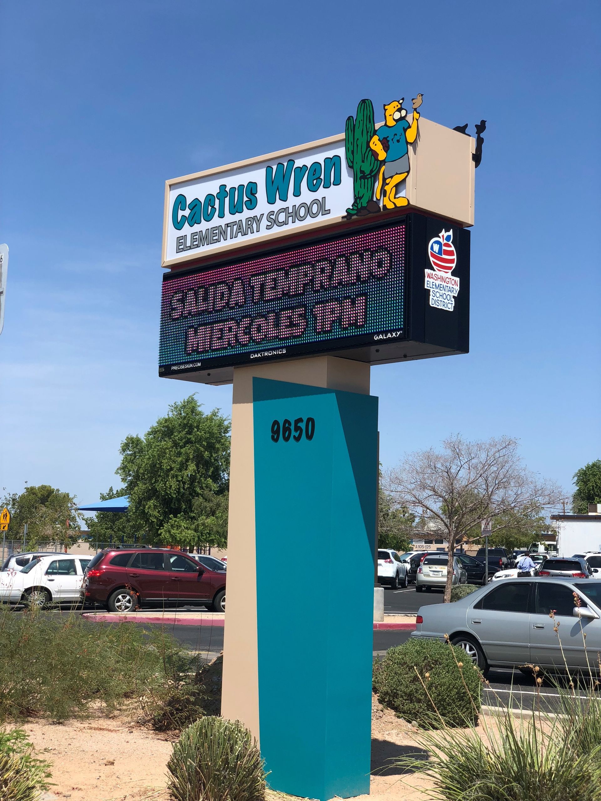 Cactus Wren Elementary School sign with digital display, teal, beige, and blue, under a sunny sky.