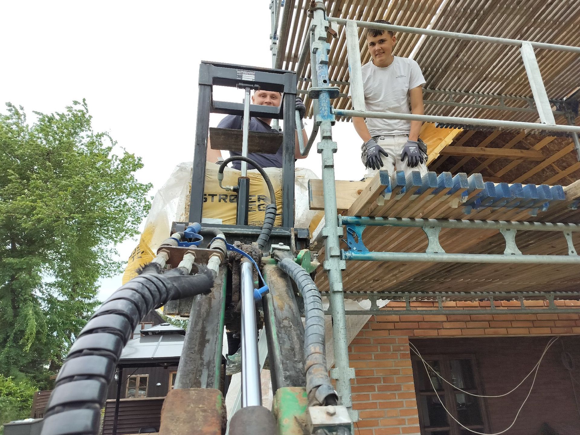 En mand står på et stillads ved siden af ​​en gaffeltruck.