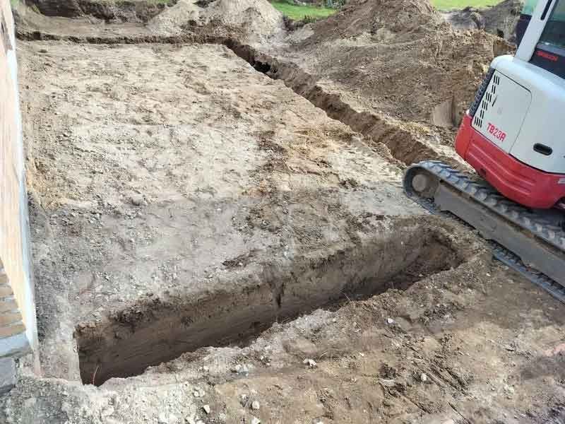En lille gravemaskine er ved at grave et hul i jorden.