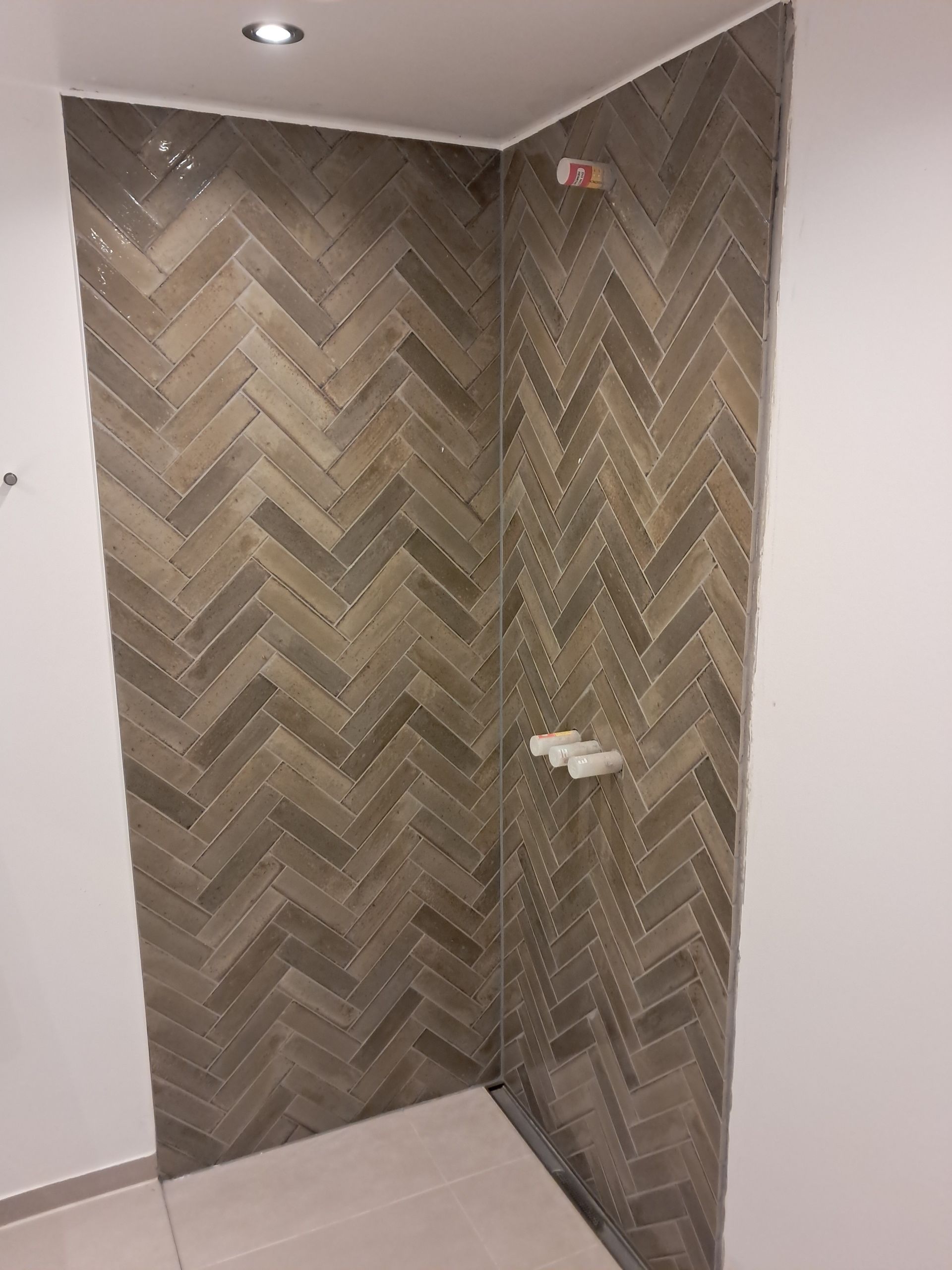 En brusekabine med sildebensmønster på væggen.