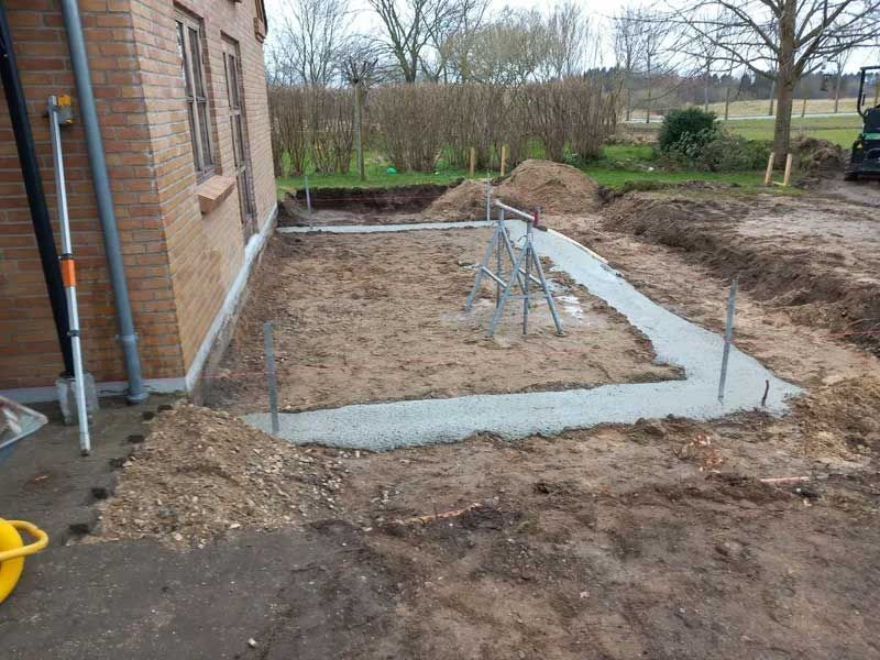 Der bygges en betongang foran en murstensbygning.