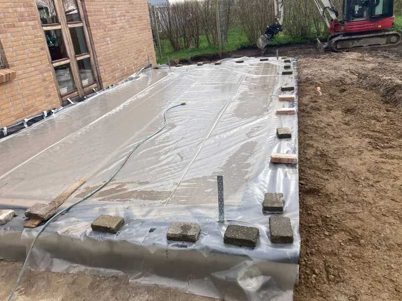 Et stort stykke plastik sidder på toppen af ​​en jordmark ved siden af ​​en murstensbygning.