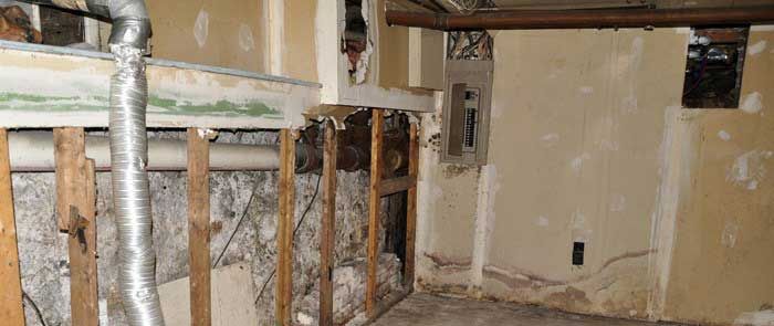 En kælder med træbjælker og rør, der kommer ud af væggene.