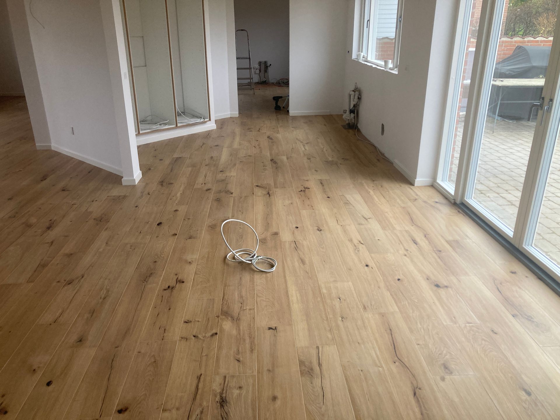 Et tomt rum med trægulv og glasskydedøre.