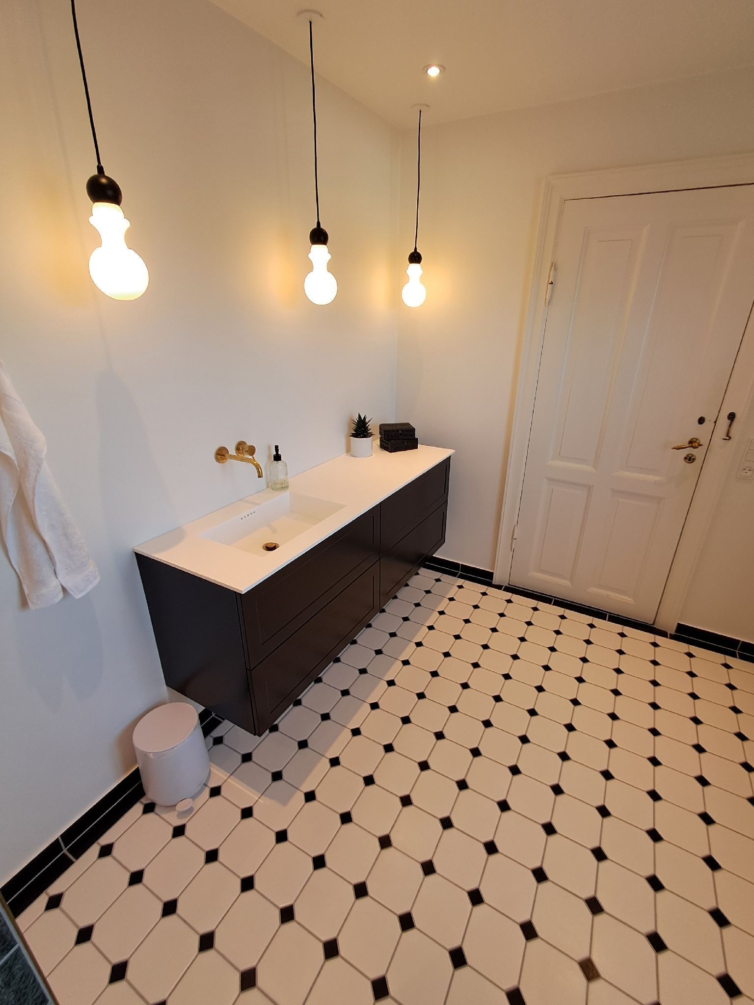 Et badeværelse med sorte og hvide klinker og en vask