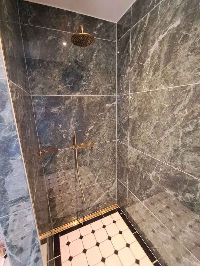 En bruser med et sort og hvidt klinkegulv og et brusehoved.