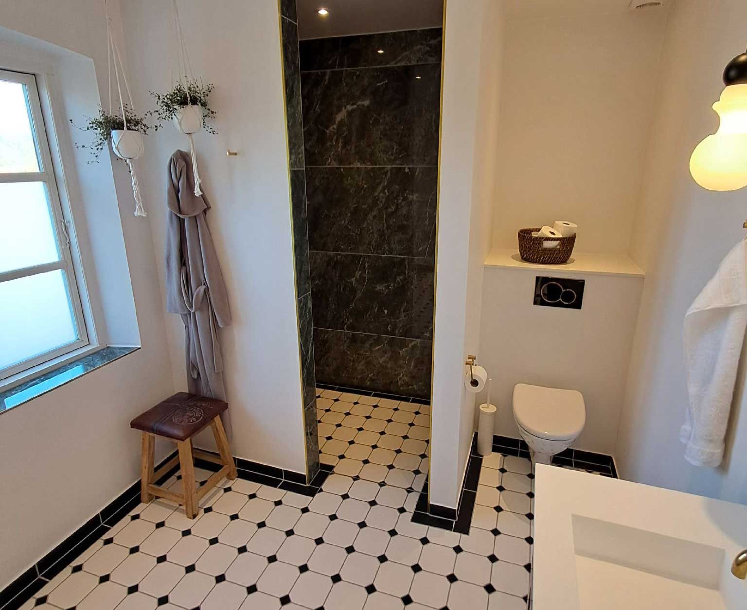 Et badeværelse med toilet, håndvask og vindue