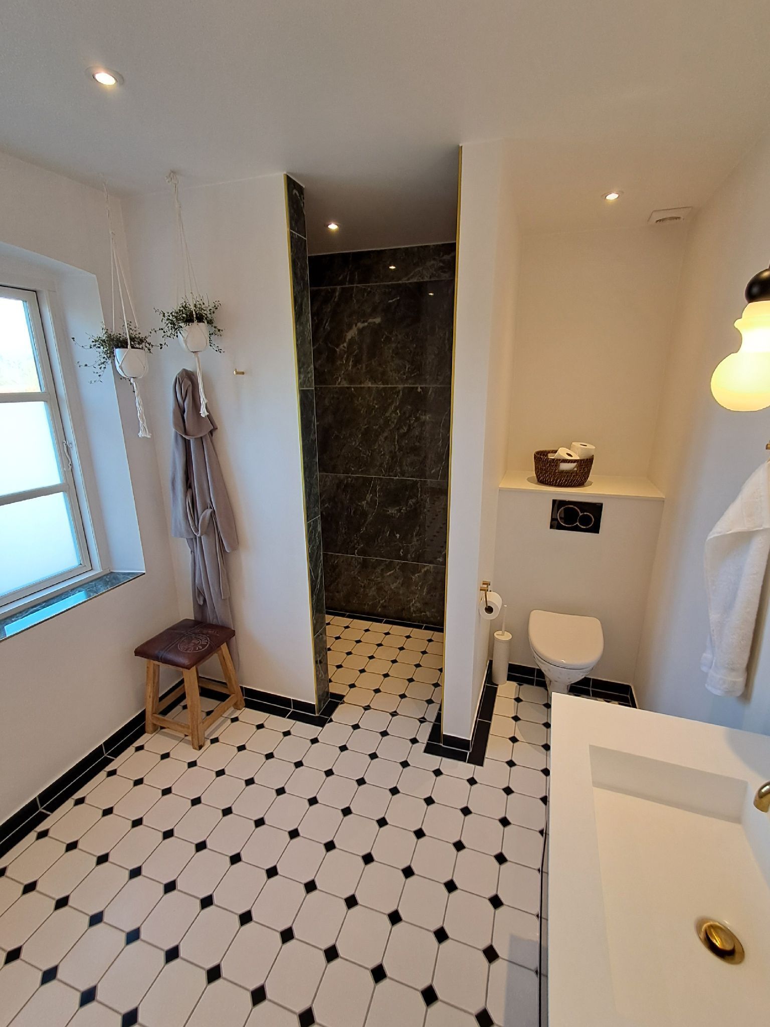 Et badeværelse med toilet, håndvask og bruser.