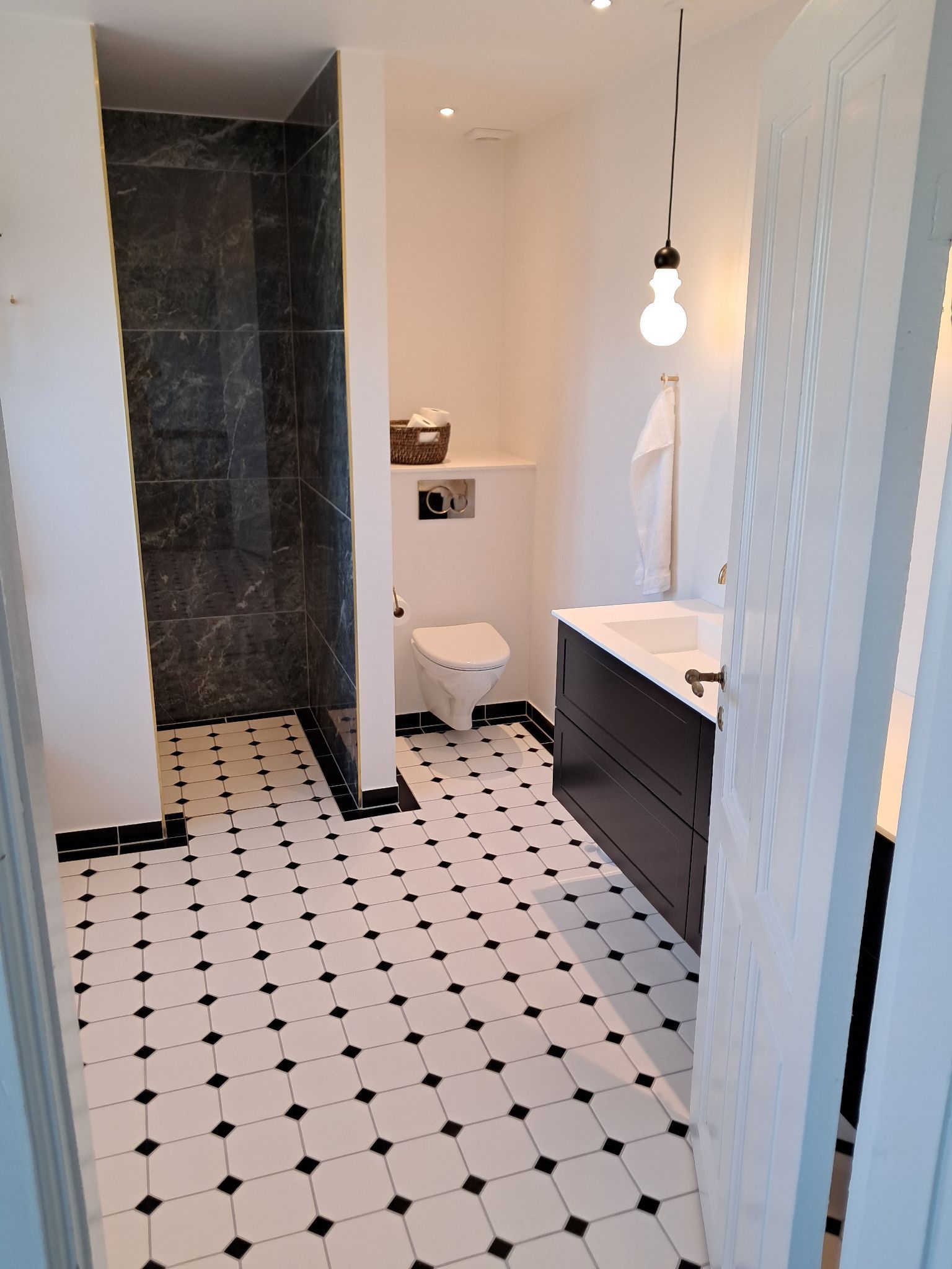 Et badeværelse med sorte og hvide klinker og et toilet