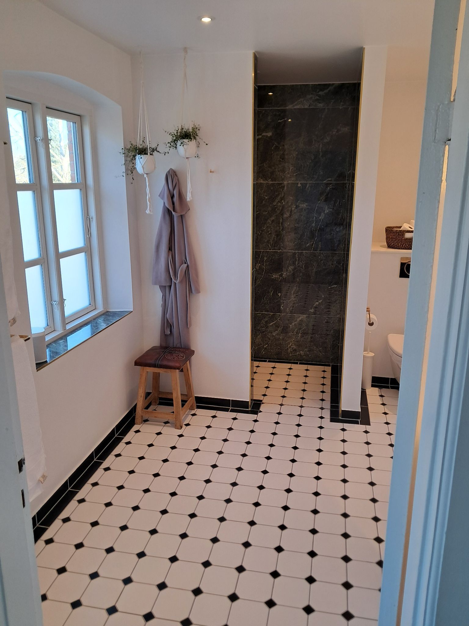 Et badeværelse med sort og hvid klinkegulv