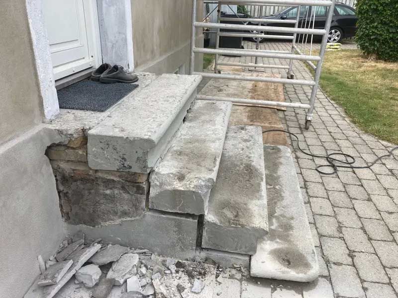 Et sæt betontrin, der sidder på toppen af ​​et murstensfortov ved siden af ​​en bygning.