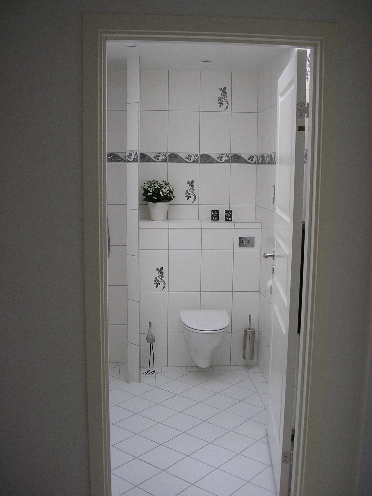 Et badeværelse med hvide klinker og et toilet