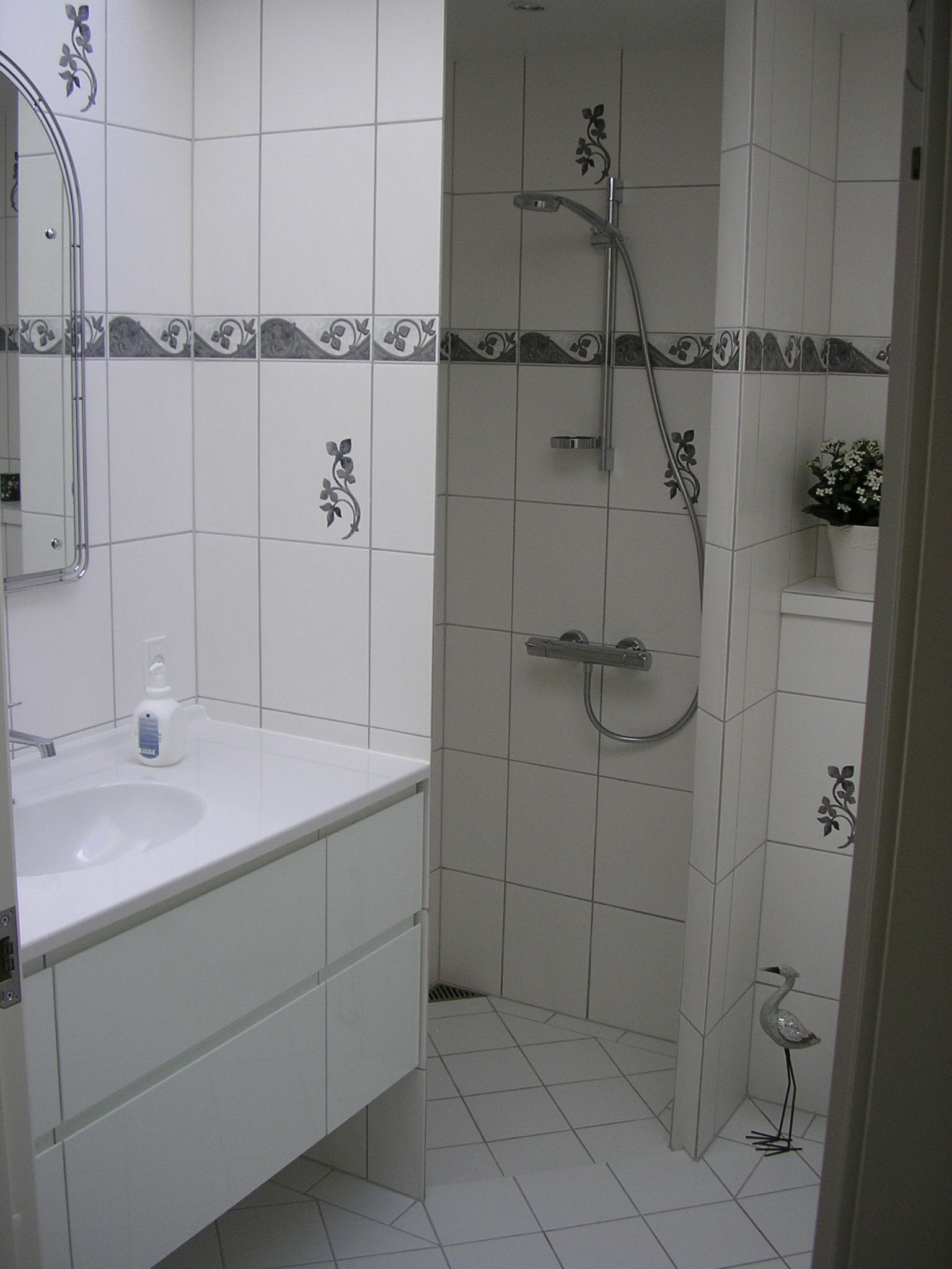 Et badeværelse med en vask, et spejl og en bruser