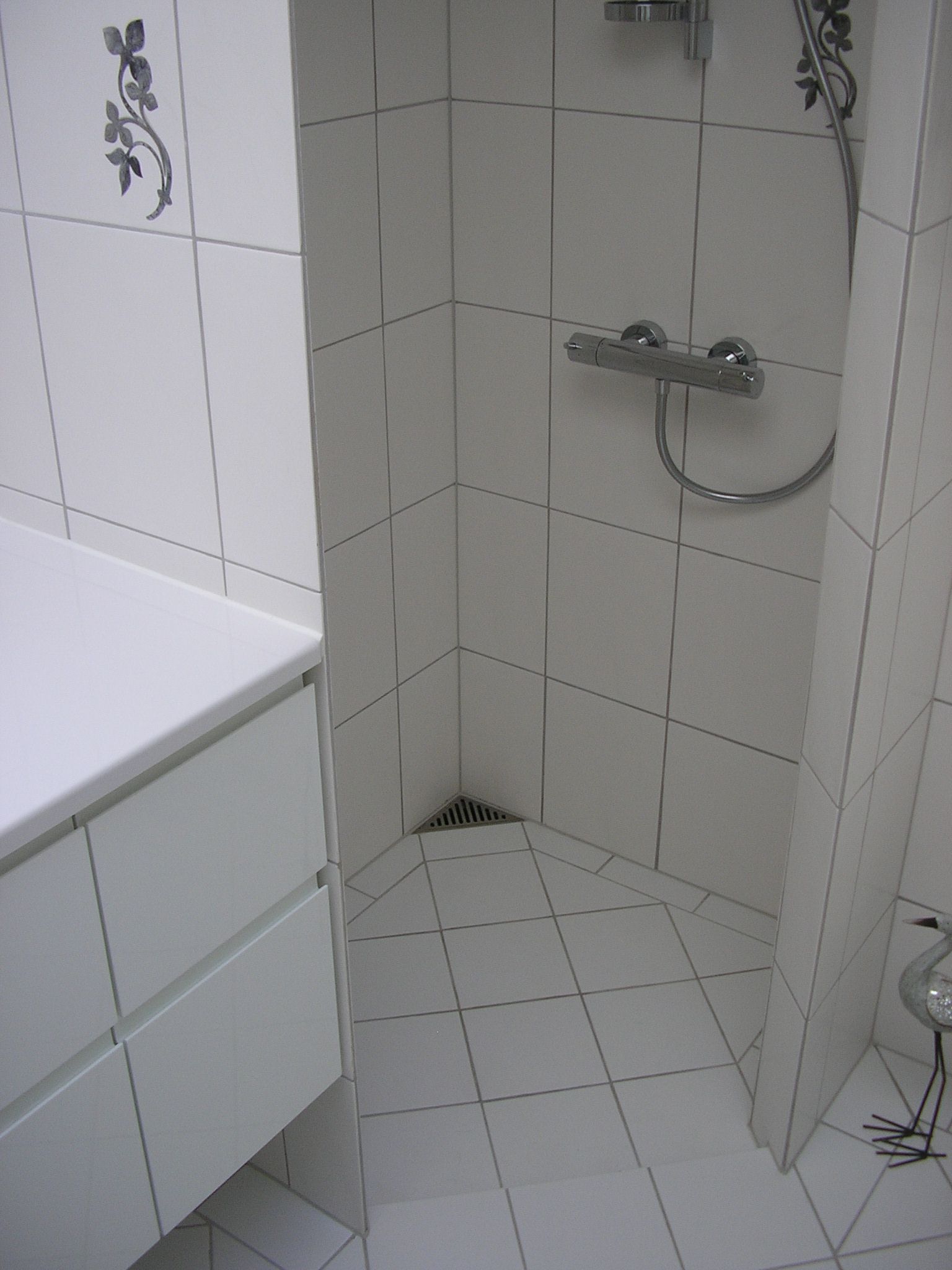 Et badeværelse med hvide klinker og bruseniche