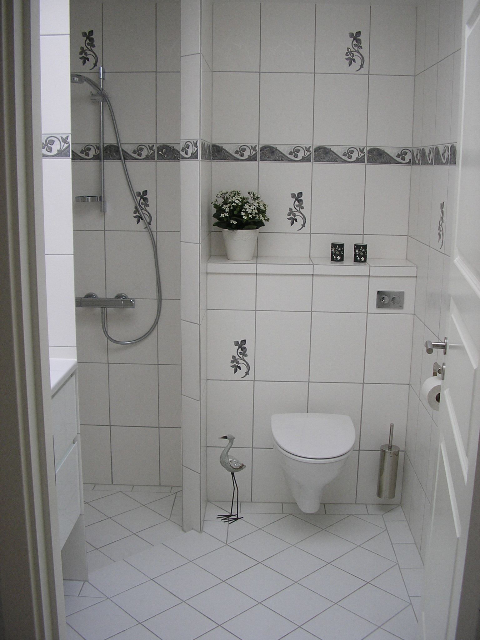 Et badeværelse med hvide klinker og et toilet