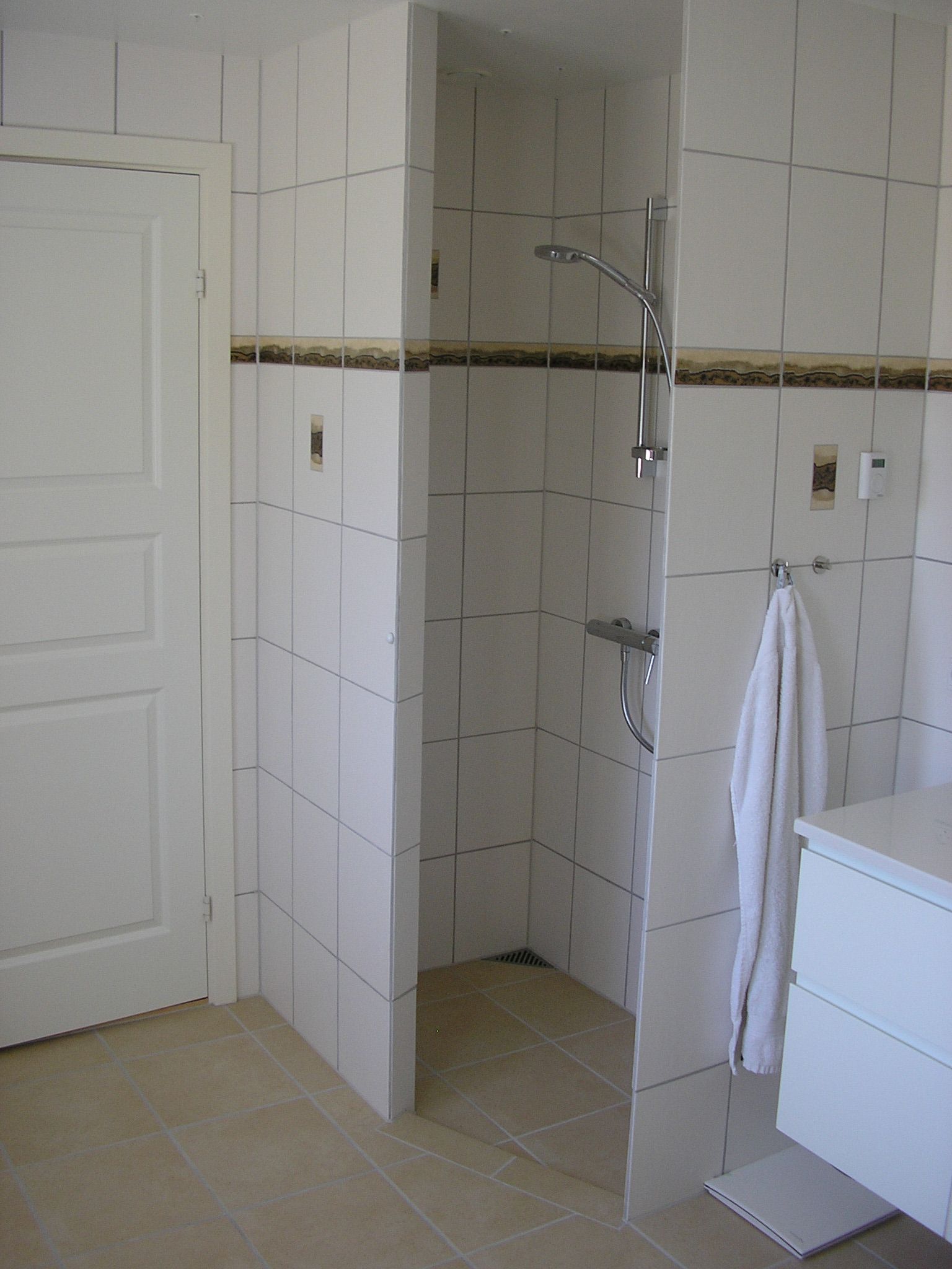 Et badeværelse med hvide klinker og bruseniche