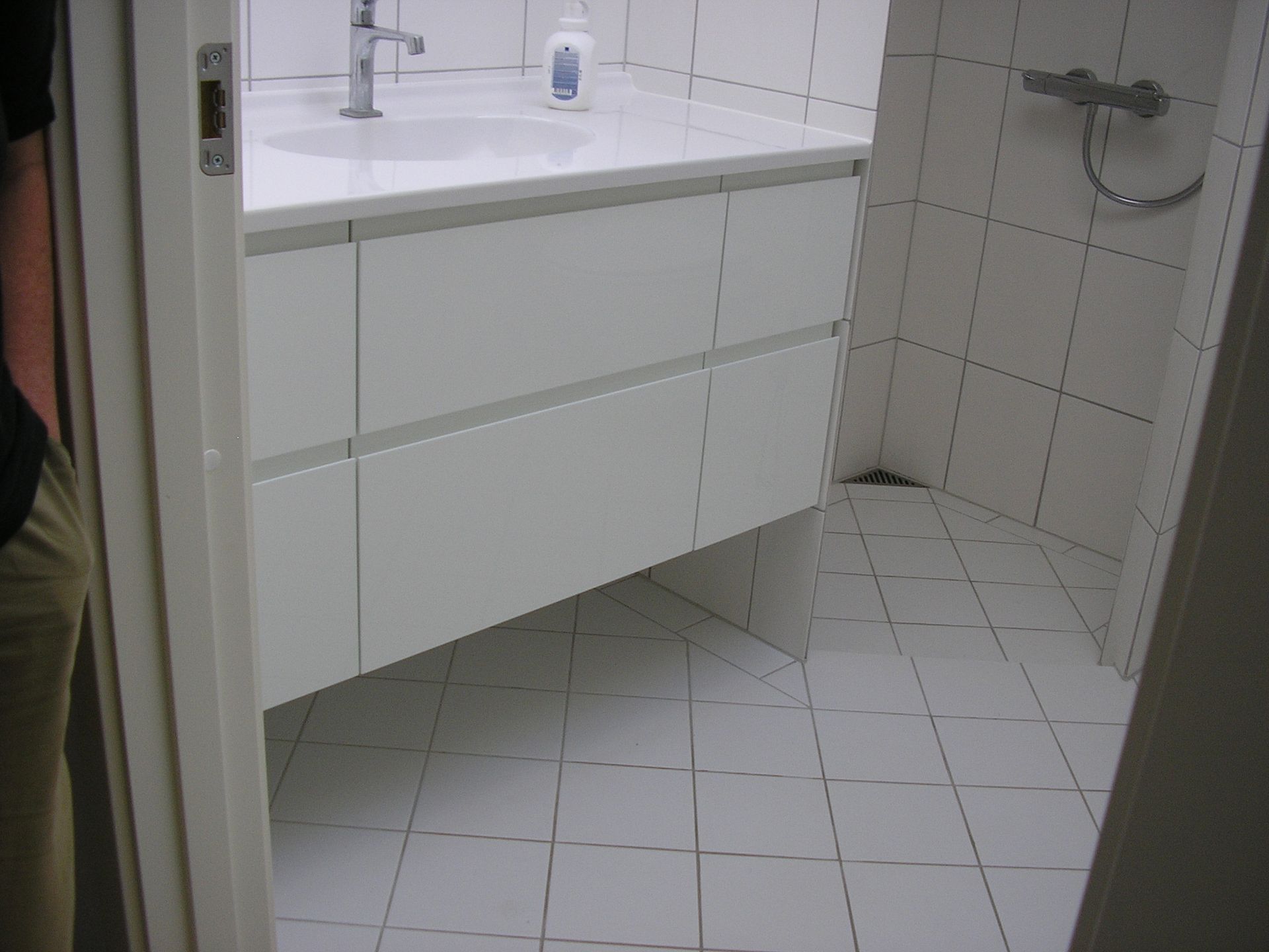 Et badeværelse med hvide klinker og en vask