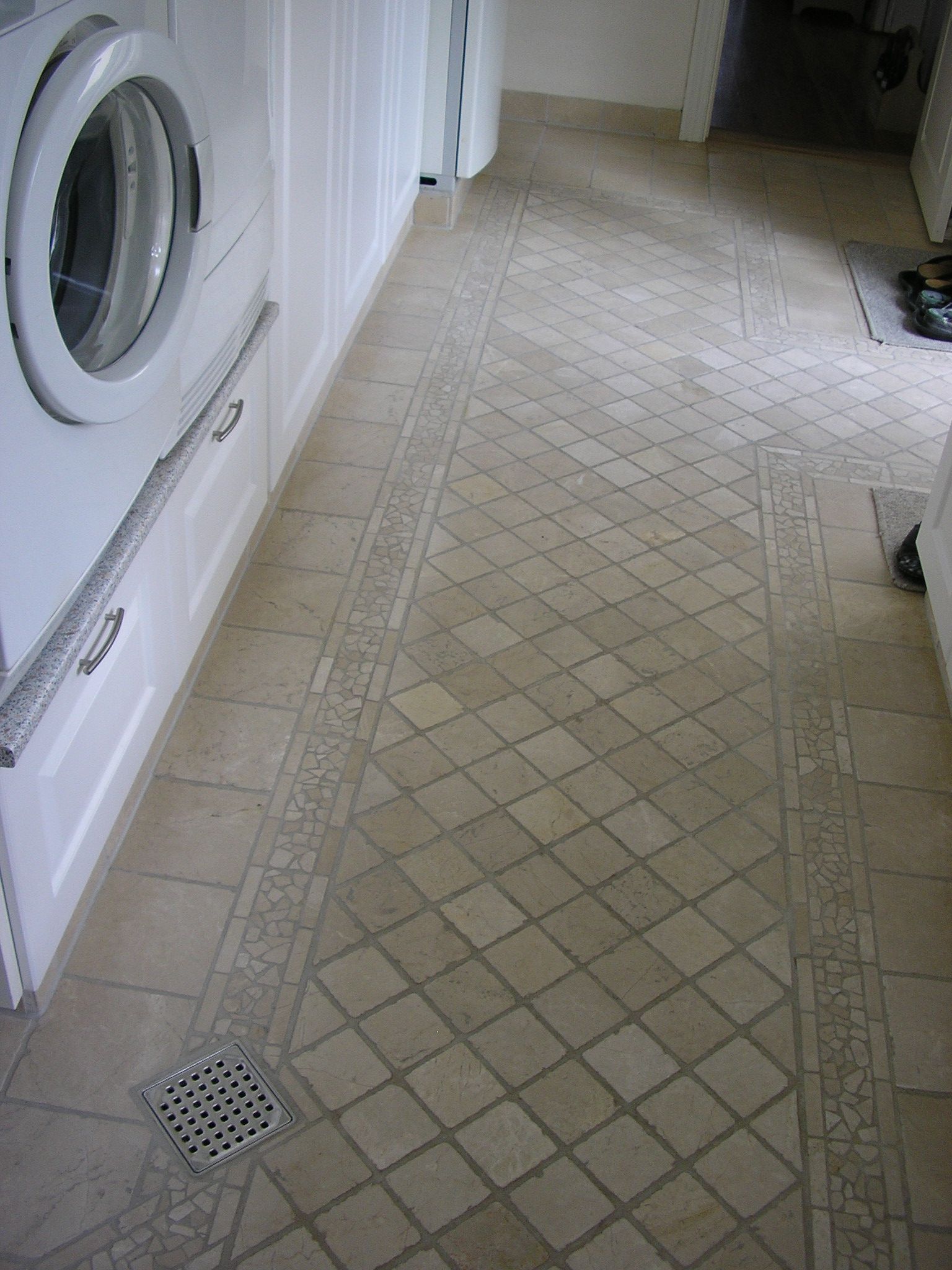 Et vaskerum med vaskemaskine og tørretumbler samt klinkegulv