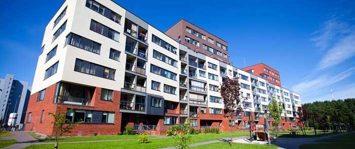 En stor lejlighedsbygning med mange vinduer på en solskinsdag.