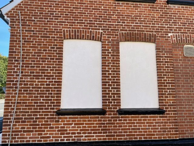 En murstensbygning med to vinduer, der er tilklædte